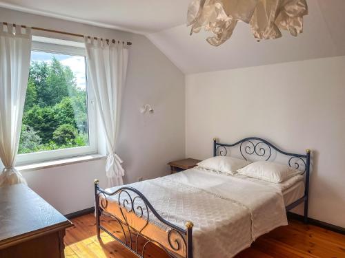 a bedroom with a bed and a large window at W Ogrodzie Dla Gości in Sasino