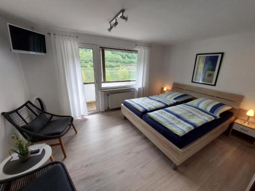 a bedroom with a bed and a chair and a television at Pension Mosella, Gästezimmer in Sankt Aldegund