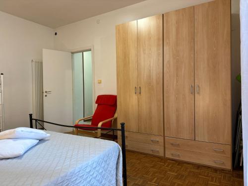 a bedroom with a bed and a cabinet and a red chair at Villa Bucchi in Lido di Spina