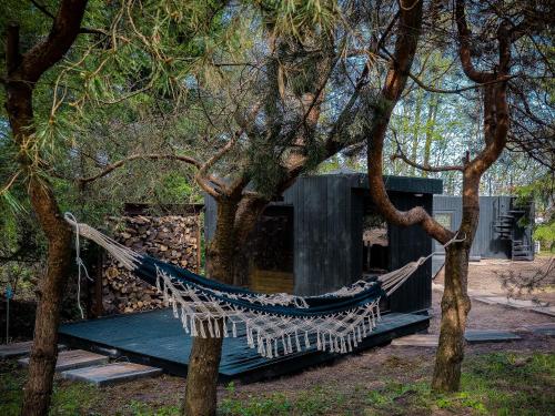 a hammock between two trees in front of a building at W Ogrodzie Dla Gości in Sasino