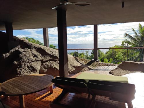 a room with a table and chairs on a balcony at Maison Gaia Seychelles, unobstructed views over the ocean and into the sunset in Glacis