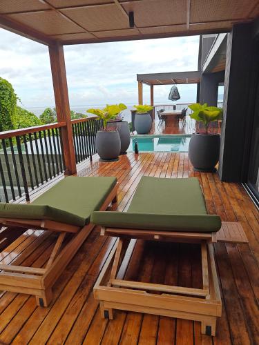 a deck with chairs and tables on a porch at Maison Gaia Seychelles, unobstructed views over the ocean and into the sunset in Glacis