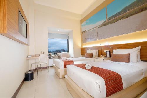 a hotel room with two beds and a desk at Pandanaran Prawirotaman Yogyakarta in Yogyakarta