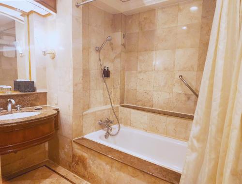 a bathroom with a shower and a tub and a sink at Richmonde Hotel Ortigas in Manila