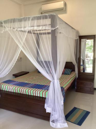 ein Bett mit Baldachin in einem Zimmer in der Unterkunft Aroma Guest House in Mirissa