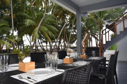 a dining room with tables and chairs and palm trees at Fehi Velaa Stay in Dhonfanu