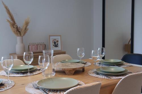 a wooden table with plates and wine glasses on it at Le Loft D'Oc - Duplex 117m2 - 2 chambres et jardin in Launaguet