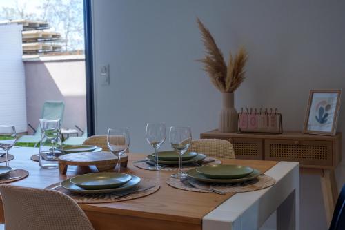 a dining room table with plates and wine glasses at Le Loft D'Oc - Duplex 117m2 - 2 chambres et jardin in Launaguet