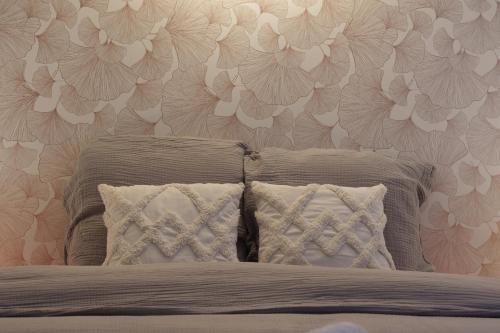 1 cama con 2 almohadas y una pared con flores en Le Loft D'Oc - Duplex 117m2 - 2 chambres et jardin, en Launaguet