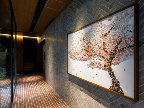 a large painting of a tree on a wall at &Here TOKYO UENO in Tokyo