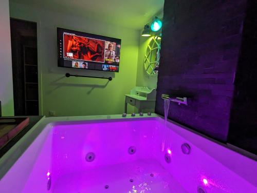 y baño con bañera rosa y TV. en Logements Ault - Détente et Confort en Baie de Somme, en Ault