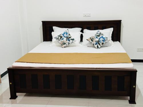 a bed with white sheets and blue and white pillows at Hikka Garden Villa in Hikkaduwa