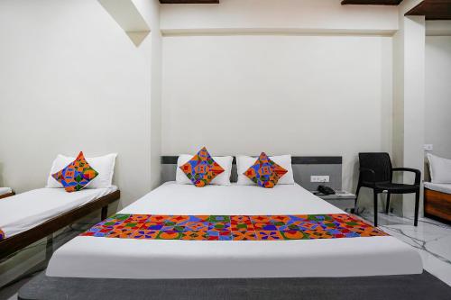 a bedroom with a white bed with a colorful comforter at FabHotel Priya Lodging, near Ojhar Airport in Nashik