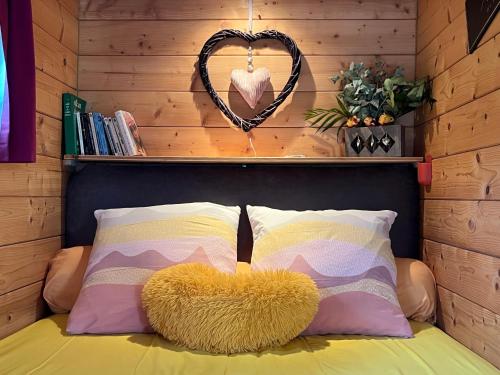 a bed with two pillows and a heart sign on a wall at Roul'hôtes évasion in Clamerey