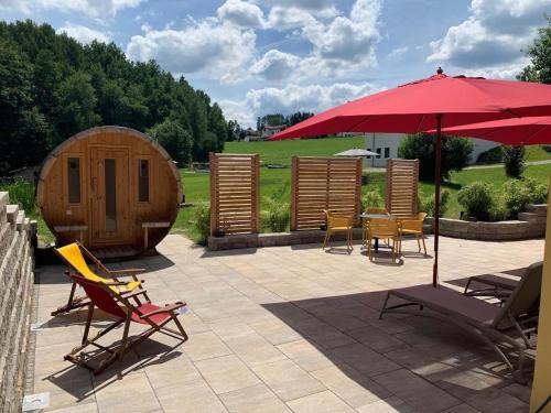 a patio with a table and chairs and an umbrella at Feriendorf Schwarzholz in Viechtach