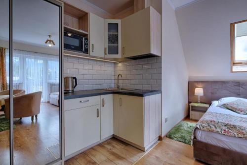 a bedroom with a bed and a kitchen with a sink at Pensjonat Dawidek in Zakopane