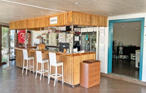 a kitchen with a bar with white stools at Jasmin Pansiyon Çıralı in Cıralı