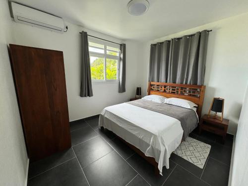 Un dormitorio con una cama grande y una ventana en Maison de 2 chambres avec vue sur la mer jardin clos et wifi a Gourbeyre a 1 km de la plage, en Gourbeyre