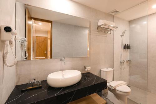 a bathroom with a sink and a toilet and a mirror at Azana Style Hotel Tulungagung in Tulungagung