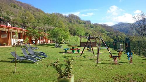 a playground with a bunch of swings in the grass at Apartamentos Rurales Balcón Real Senda del Oso in Campiello