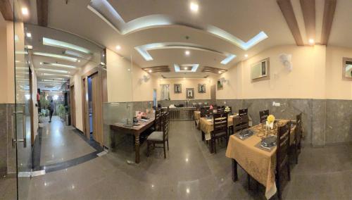 a dining room with tables and chairs in a restaurant at Hotel Royal Inn igi in New Delhi