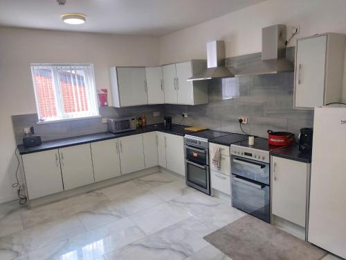 una cocina con armarios blancos y electrodomésticos negros en Masfol comfort zone en Oldham