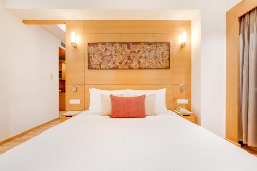 a bedroom with a white bed with a red pillow at Lemon Tree Hotel Chandigarh in Chandīgarh