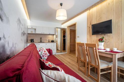 a living room with a red couch and a kitchen at Pensjonat Dawidek in Zakopane