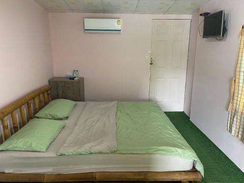 a small bedroom with a bed with green sheets at Khlongsaeng farmstay in Ban Ta Khun