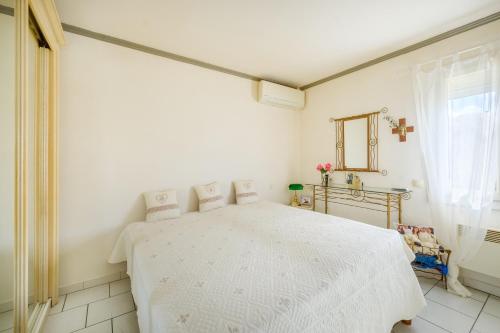 ein weißes Schlafzimmer mit einem weißen Bett in einem Zimmer in der Unterkunft Villa 6 pers avec piscine in Le Tignet