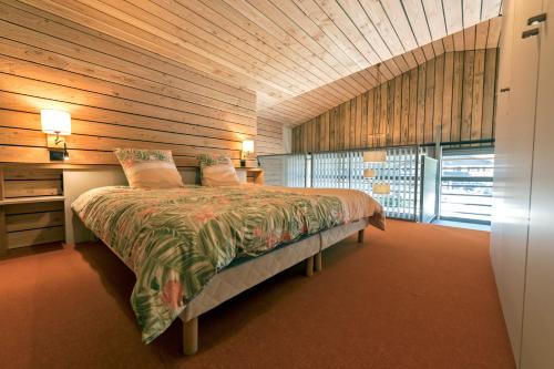 a bedroom with a bed and a wooden wall at le petit ballon in Ventron