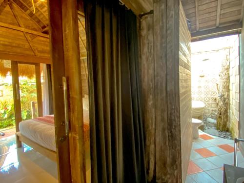a room with a bed and a window with curtains at Umah Suta Sari in Dalung
