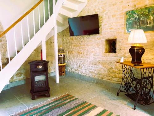 sala de estar con estufa de leña y TV en Maison Chinsa, en Saint-Angeau