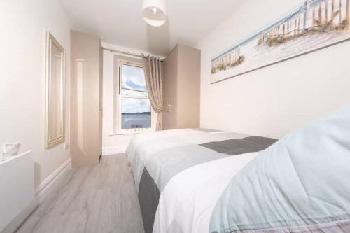 een witte slaapkamer met een bed en een raam bij Unit 2 Island View Apartments With Stunning Harbour View in Cobh
