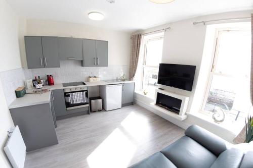 een keuken en een woonkamer met een blauwe bank bij Unit 2 Island View Apartments With Stunning Harbour View in Cobh