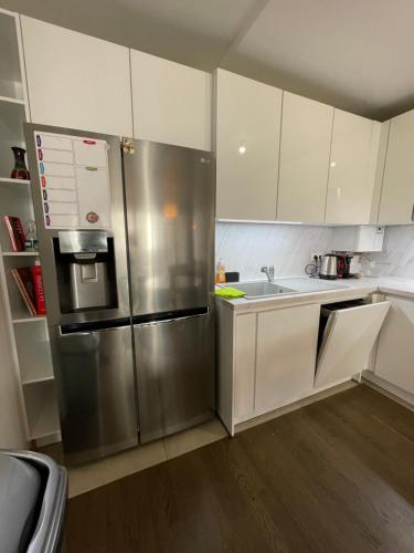 a kitchen with white cabinets and a stainless steel refrigerator at Sweet Escape Paris Centre - 3 bds- terrasse - Stade de France - Montmartre in Saint-Ouen