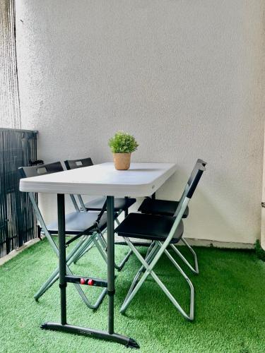 - une table avec deux chaises et une plante en pot dans l'établissement Sweet Escape Paris Centre - 3 bds- terrasse - Stade de France - Montmartre, à Saint-Ouen