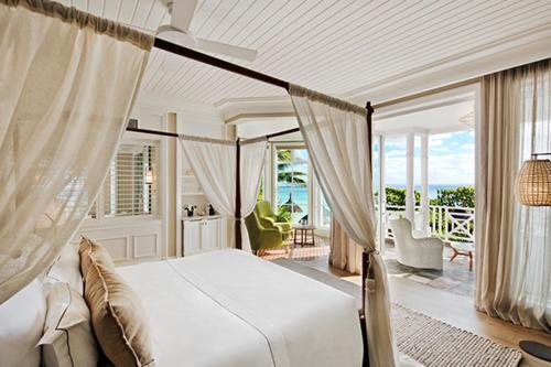 a bedroom with a canopy bed with a view of the ocean at Heritage Le Telfair Golf & Wellness Resort in Bel Ombre