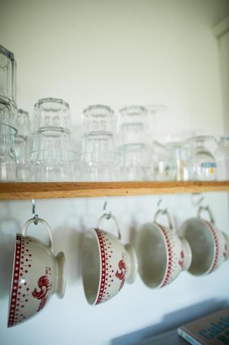 a row of coffee cups on a shelf with glasses at Domaine du Boscq in Parleboscq