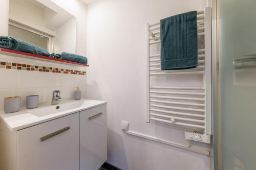 une salle de bain blanche avec un lavabo et un miroir dans l'établissement Le Bercail - Joli studio proche commodités, à Clermont-Ferrand