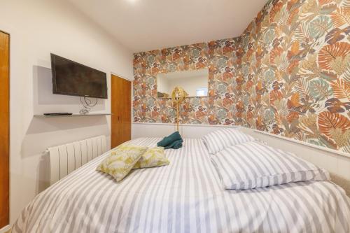 - une chambre avec un lit et une télévision murale dans l'établissement Le Bercail - Joli studio proche commodités, à Clermont-Ferrand