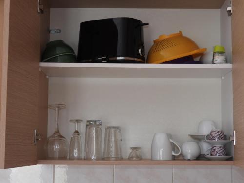 a shelf with various glass items in a kitchen at Studios Nina in Amoopi