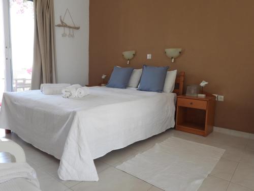 um quarto com uma grande cama branca com almofadas azuis em Studios Nina em Amoopi