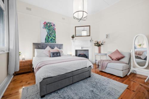a bedroom with a bed and a couch and a fireplace at Mrs Percivals heritage luxury and romance with outdoor deep soak tub in Victor Harbor