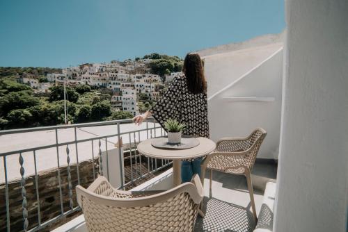 Eine Frau steht auf einem Balkon mit einem Tisch und Stühlen in der Unterkunft VOLTO Suite in Kóronos