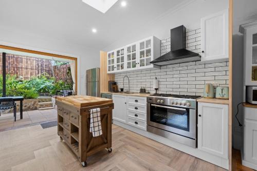 a kitchen with white cabinets and a stove top oven at Mrs Percivals heritage luxury and romance with outdoor deep soak tub in Victor Harbor