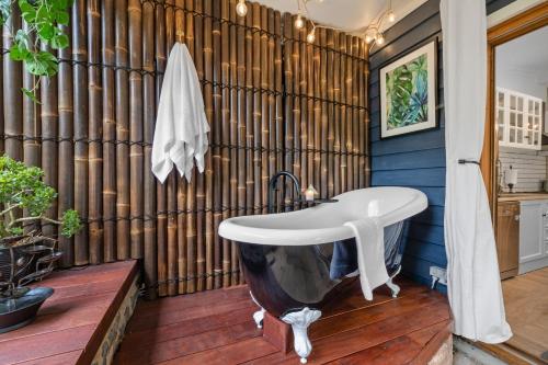 a bathroom with a tub and a wooden wall at Mrs Percivals heritage luxury and romance with outdoor deep soak tub in Victor Harbor