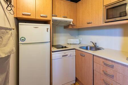 La cuisine est équipée d'un réfrigérateur blanc et de placards en bois. dans l'établissement Duplex la Solana, à Err