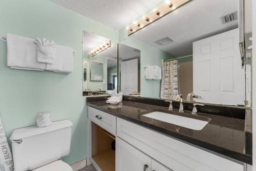 a bathroom with a sink and a toilet and a mirror at Commodore 504 in Panama City Beach