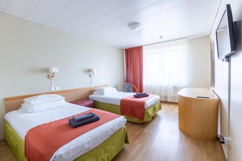 a hotel room with two beds and a flat screen tv at Peoleo Hotell in Tallinn